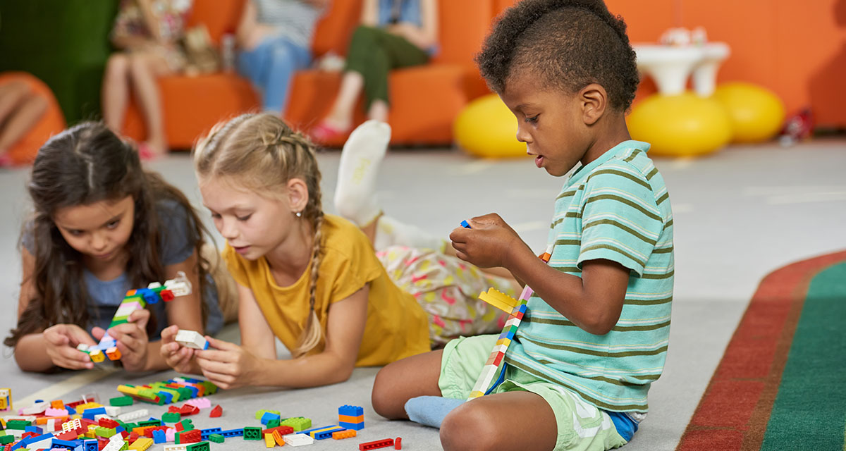 Crianças brincando com brinquedos espalhados no chão